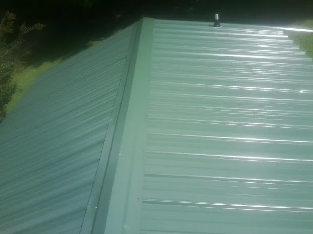 New green metal panels meeting at the ridge of a roof — Flat Roof Repair work by our crew in Frenchburg