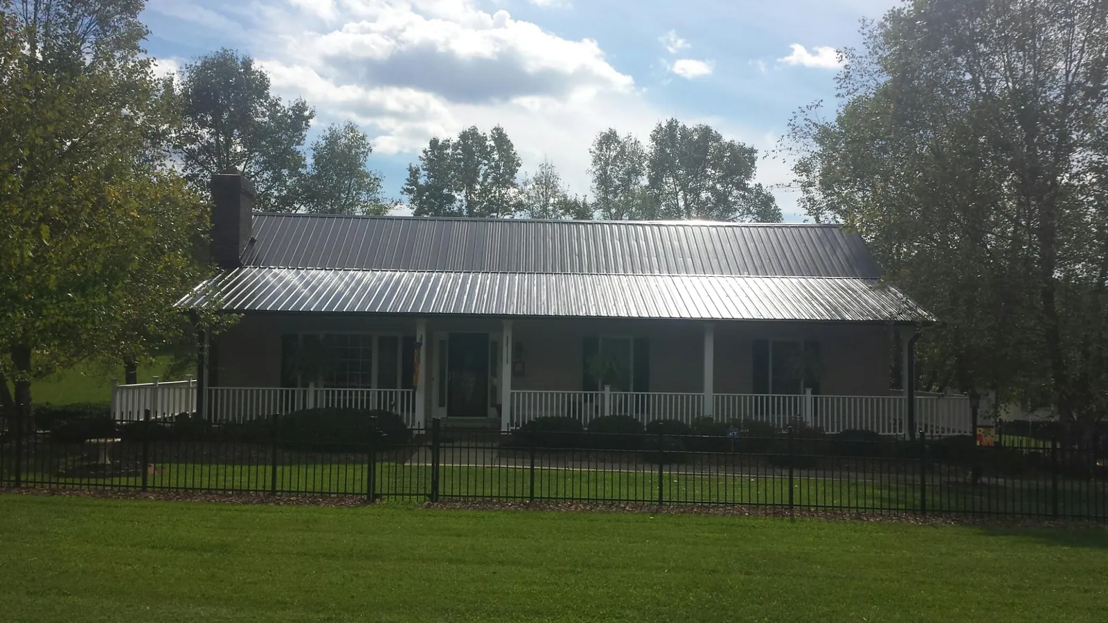 Gray metal roof on a brick ranch with a full width front porch — Gutter Guard Installation work by our crew in Frenchburg