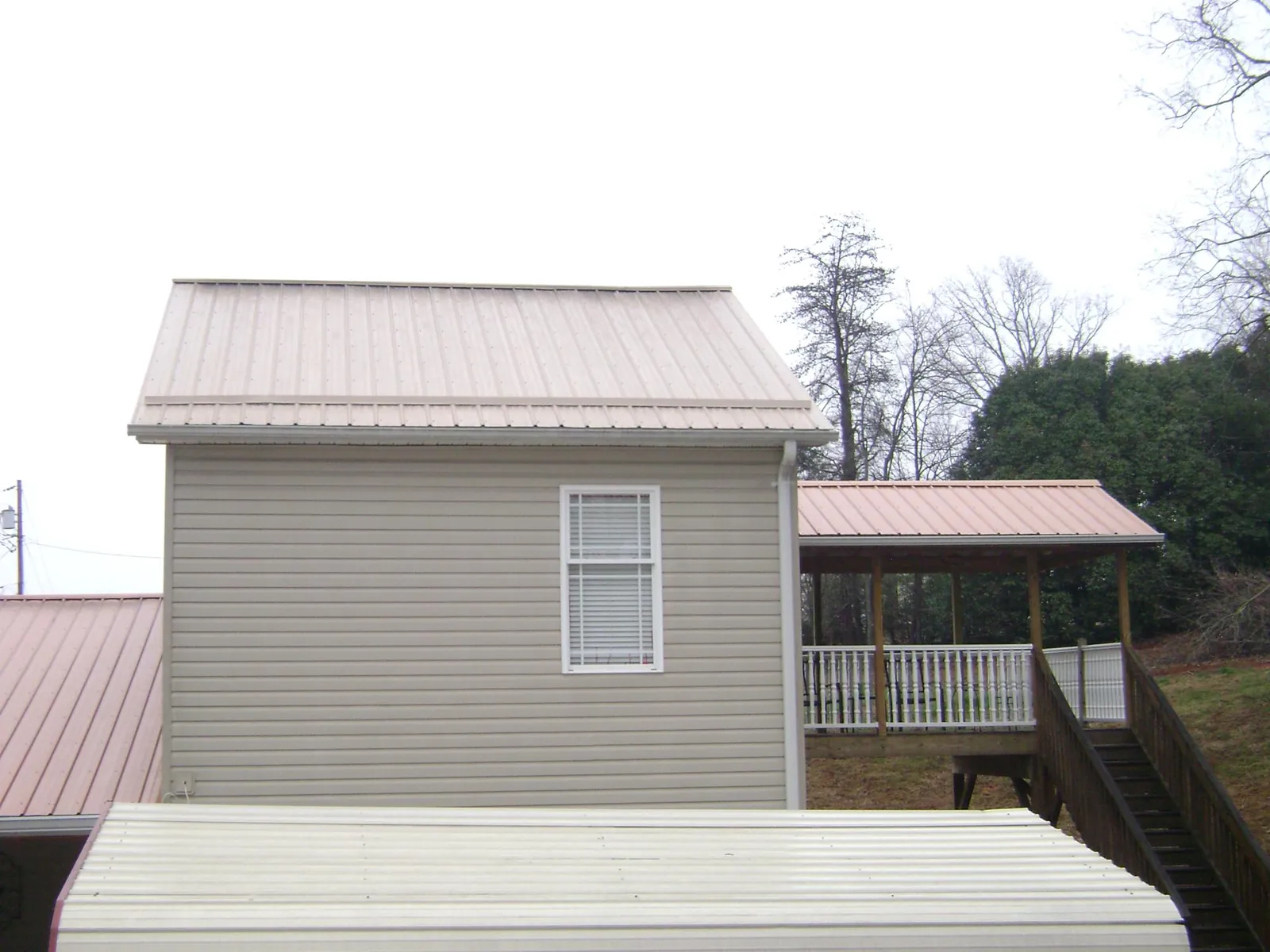 Tan metal roofs on a two story addition and attached porch, from a Roof Replacement job in Frenchburg