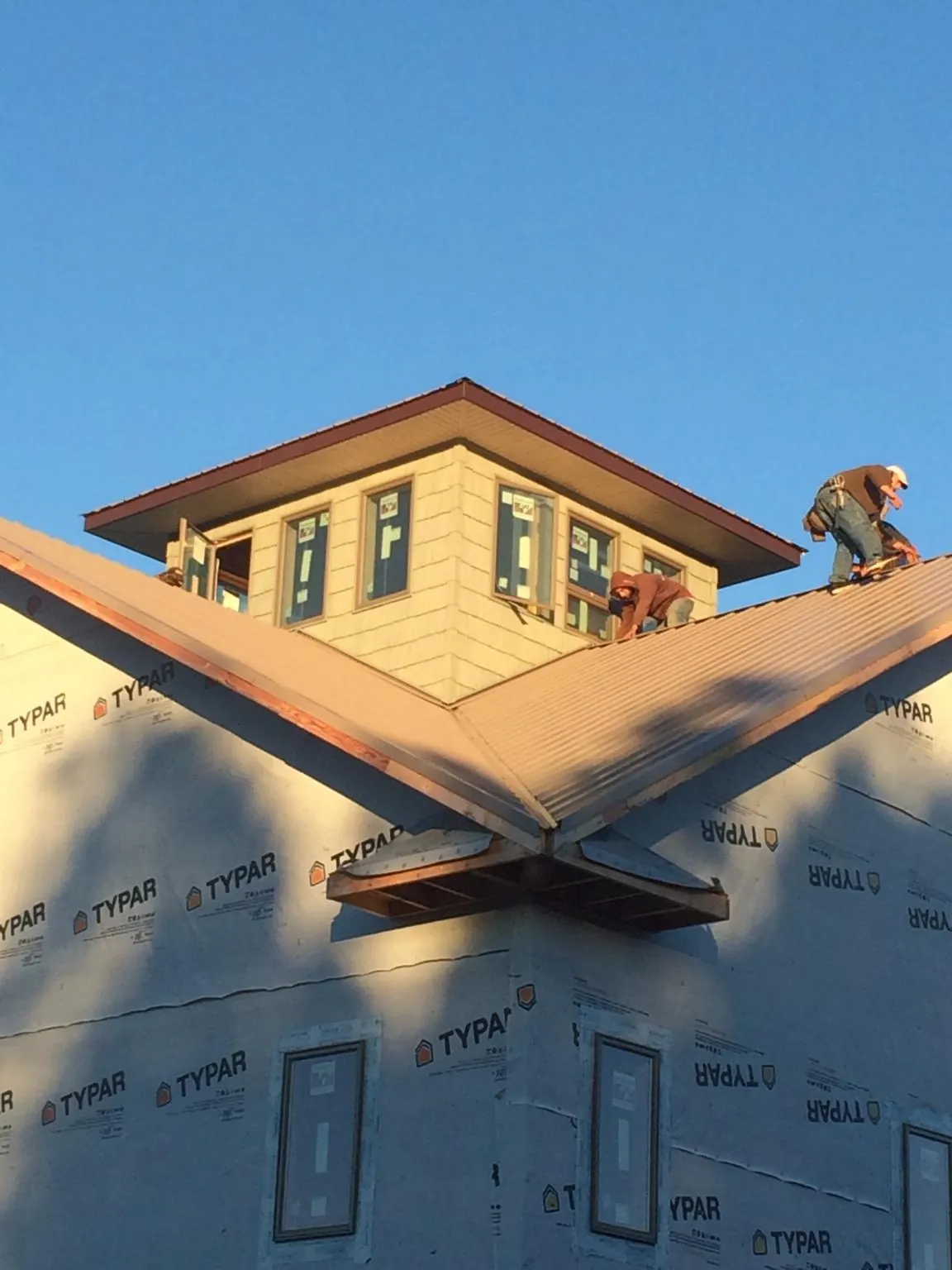 Roofers working around a rooftop cupola on a new metal roof at sunset — Roof Waterproofing in Frenchburg by Roofing Brothers